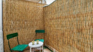 A small outdoor seating area with a bamboo wall, a round table, and two green chairs. - GuestHost - Modern 80 sqm apartment, able to comfortably accommodate up to 6 people, located on the basement floor. The property is located in the Statuto area, just outside the centre, a 5-minute walk from the Fortezza Garden and 10 minutes from the For (Firenze)