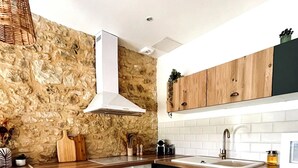 A modern kitchen with a stone wall backsplash, wooden cabinets, a stainless steel oven, and a wooden countertop. - La Grange aux Souvenirs - Perigord Noir (Les Coteaux Périgourdins)