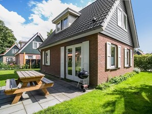A house with a brick exterior, a covered patio, and a barbecue grill. - Holiday Home With Enclosed Garden (Zonnemaire)