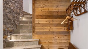 Un escalier avec des marches en pierre et une finition en bois, menant à un banc et un porte-manteau.