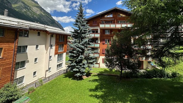 A multi-story building with balconies, surrounded by greenery and mountains. - Haus Cresta - Zermatt Paradise- Swiss Alps (Zermatt)