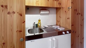 A compact kitchen with wooden cabinets, a stainless steel sink, and a gas stove. - Haus Cresta - Zermatt Paradise- Swiss Alps (Zermatt)