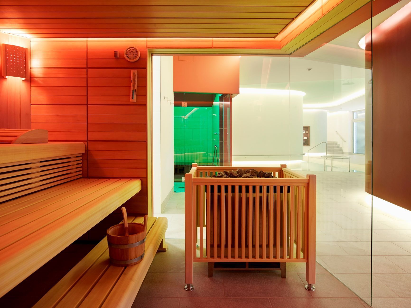 Una sauna moderna con bancos de madera y un cubo sobre un banco de madera.