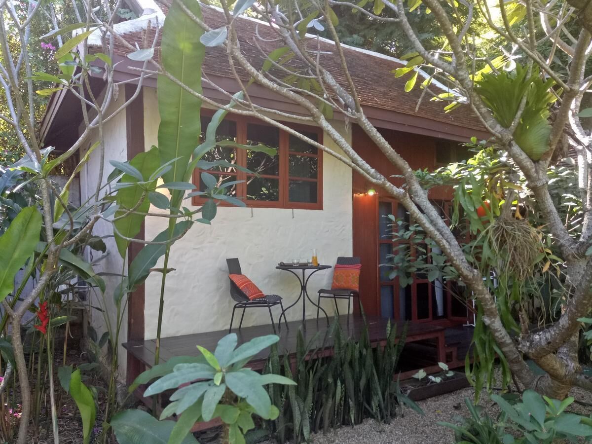 A small house with a patio area, two chairs, and a table.