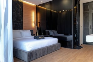 A modern hotel room with a large bed, a separate seating area, and a sliding door leading to a bathroom.