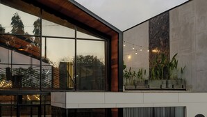 Een modern gebouw met grote ramen, een stenen muur en buitenplanten.