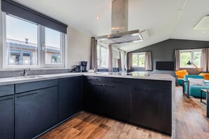 A modern kitchen with dark cabinets, a large island, and a built-in oven.
