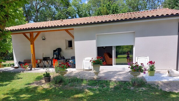 Una casa con un porche techado, puerta corrediza de vidrio y mobiliario exterior.