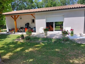 Une maison dotée d’un patio couvert, d’une porte-fenêtre coulissante et d’un espace salon extérieur.