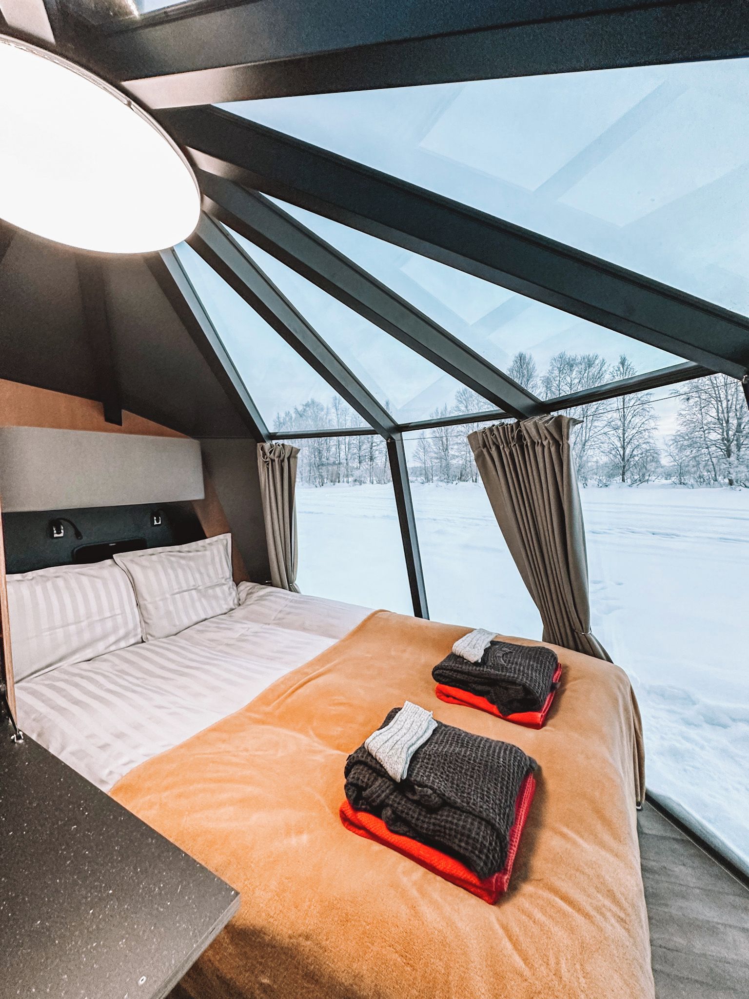 A modern interior with a bed, a window, and a view of a snowy landscape.