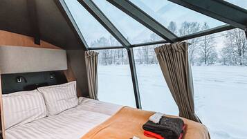 A modern interior with a bed, a window, and a view of a snowy landscape.