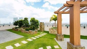 A rooftop garden with a pergola, stone planters, and a view of the city skyline. - Sunshine 100 Plaza (Mandaluyong)