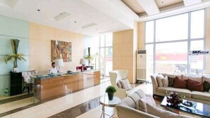A modern hotel lobby with a reception desk, seating area, and large windows. - Sunshine 100 Plaza (Mandaluyong)