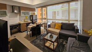 A modern living room with a sofa, coffee table, and a dining area with a table and chairs. - Sunshine 100 Plaza (Mandaluyong)