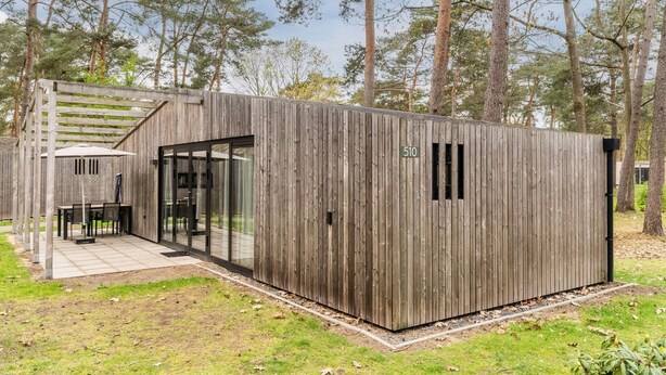A wooden cabin with a glass door entrance, a small patio area, and a number 510 sign. - Chalet Near Eindhoven in a Green Oasis (Mierlo)