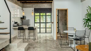 A modern kitchen with a bar area, a dining space with chairs, and a staircase leading to an upper level. - Berawa Loft 10 by Betterplace (Canggu)