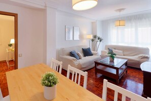 Una sala de estar con una mesa de comedor de madera, dos sofás, una mesa de centro y una lámpara.