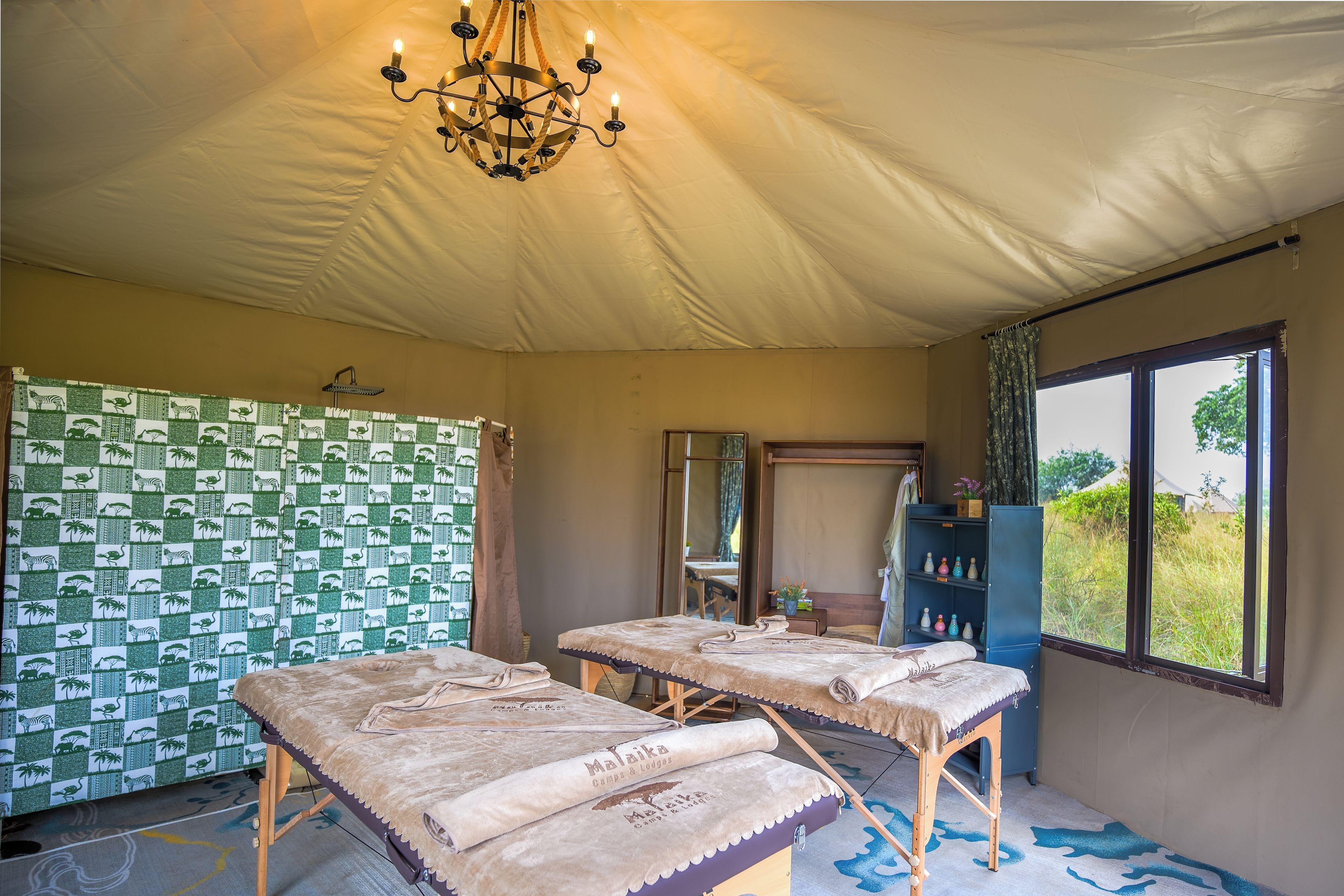 Habitación con carpa que tiene dos camas, un candelabro, ducha y vista al exterior.
