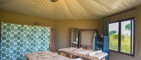 Habitación con carpa que tiene dos camas, un candelabro, ducha y vista al exterior.