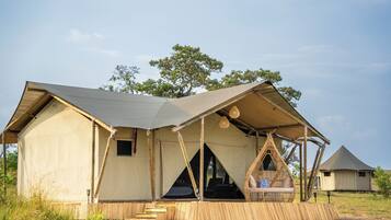A safari tent with a covered seating area and a small window.