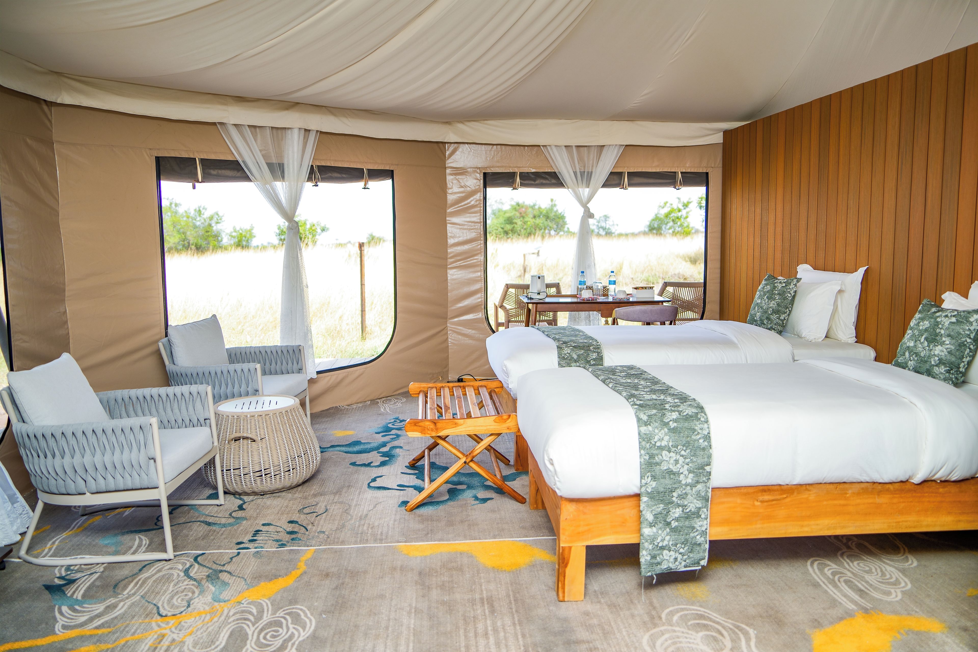 A tented accommodation with a bed, seating area, and a table with amenities.