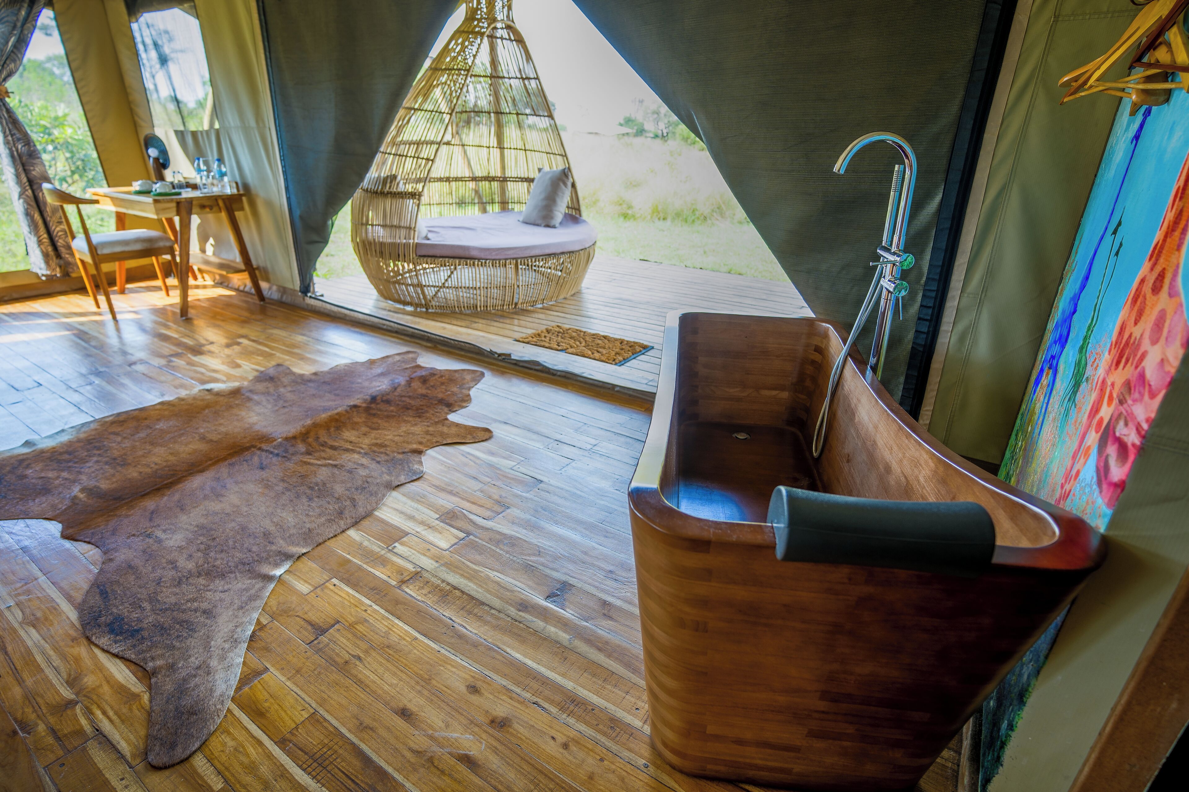 A wooden floor, a wooden bathtub, a woven hanging chair, and a fur rug.