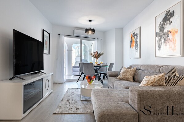A modern living room with a flat-screen TV, grey sofa, and artwork on the walls. - Fancy 2BR Retreat: Pool, Parking, Wonderful Views REF045 (Benalmádena)