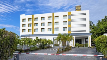 Un moderno edificio de hotel con varios pisos, techo plano y entrada protegida por una reja.