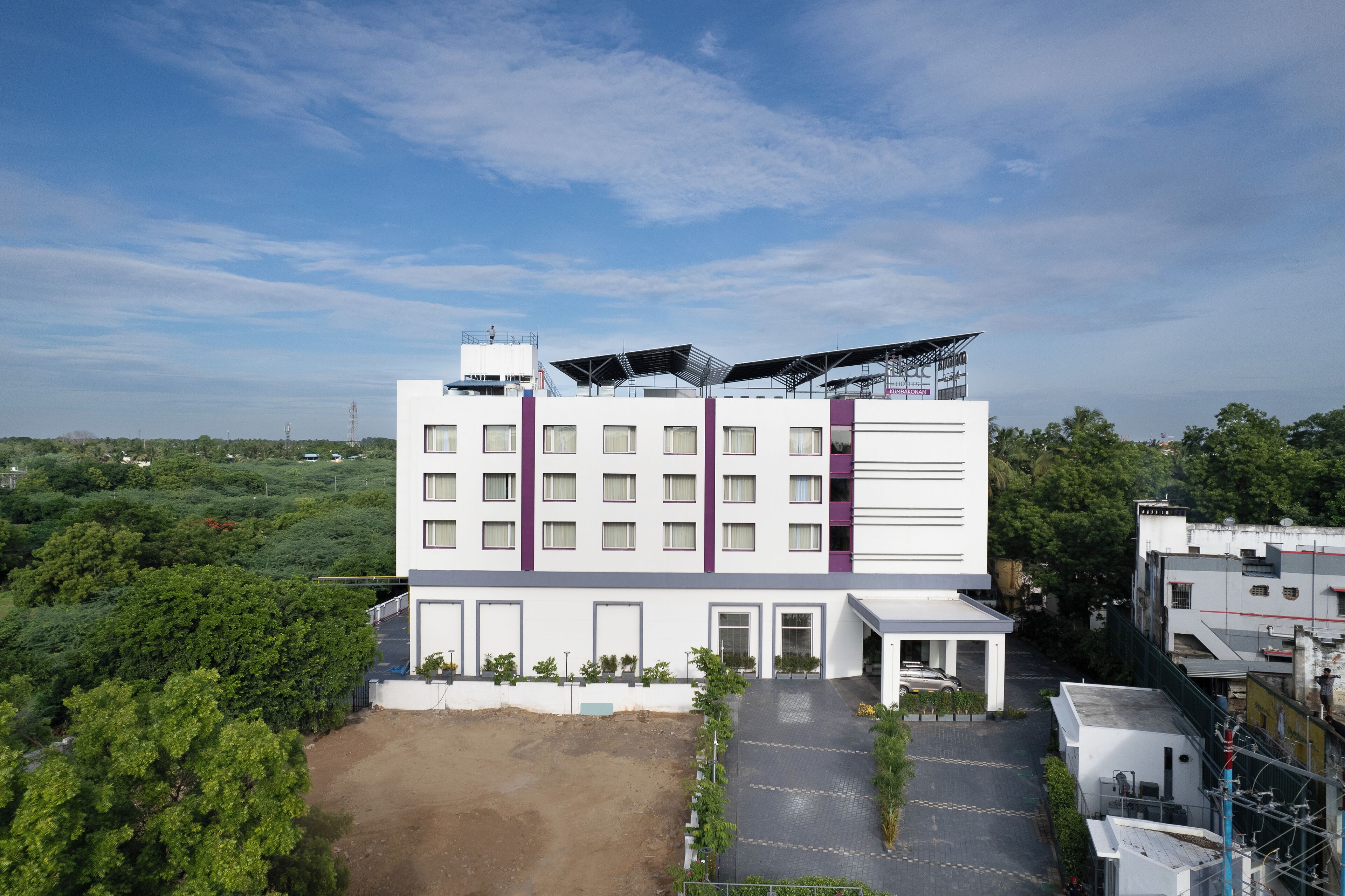 A modern building with multiple floors, a flat roof, and a paved courtyard.