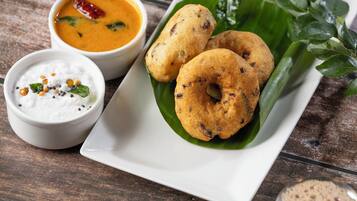 A plate of food with two fritters, a bowl of soup, a bowl of yogurt, and a small metal cup.