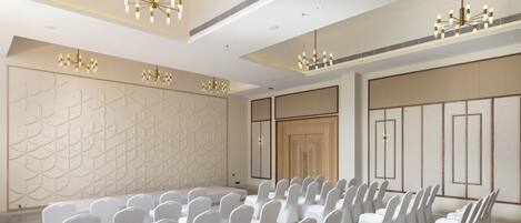 A conference room with rows of white chairs, a stage, and a decorative wall with geometric patterns.