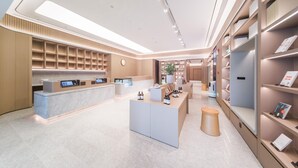 A modern hotel lobby with a reception desk, seating area, and shelves with informational materials. - Ji Hotel Shenzhen Baoan Pingzhou Subway Station (Shenzhen)