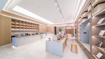 Un moderno vestíbulo de hotel con recepción, zona de estar y una gran estantería.