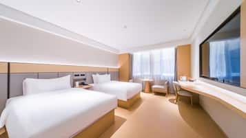 A modern hotel room with two beds, a desk, a chair, and a large window.