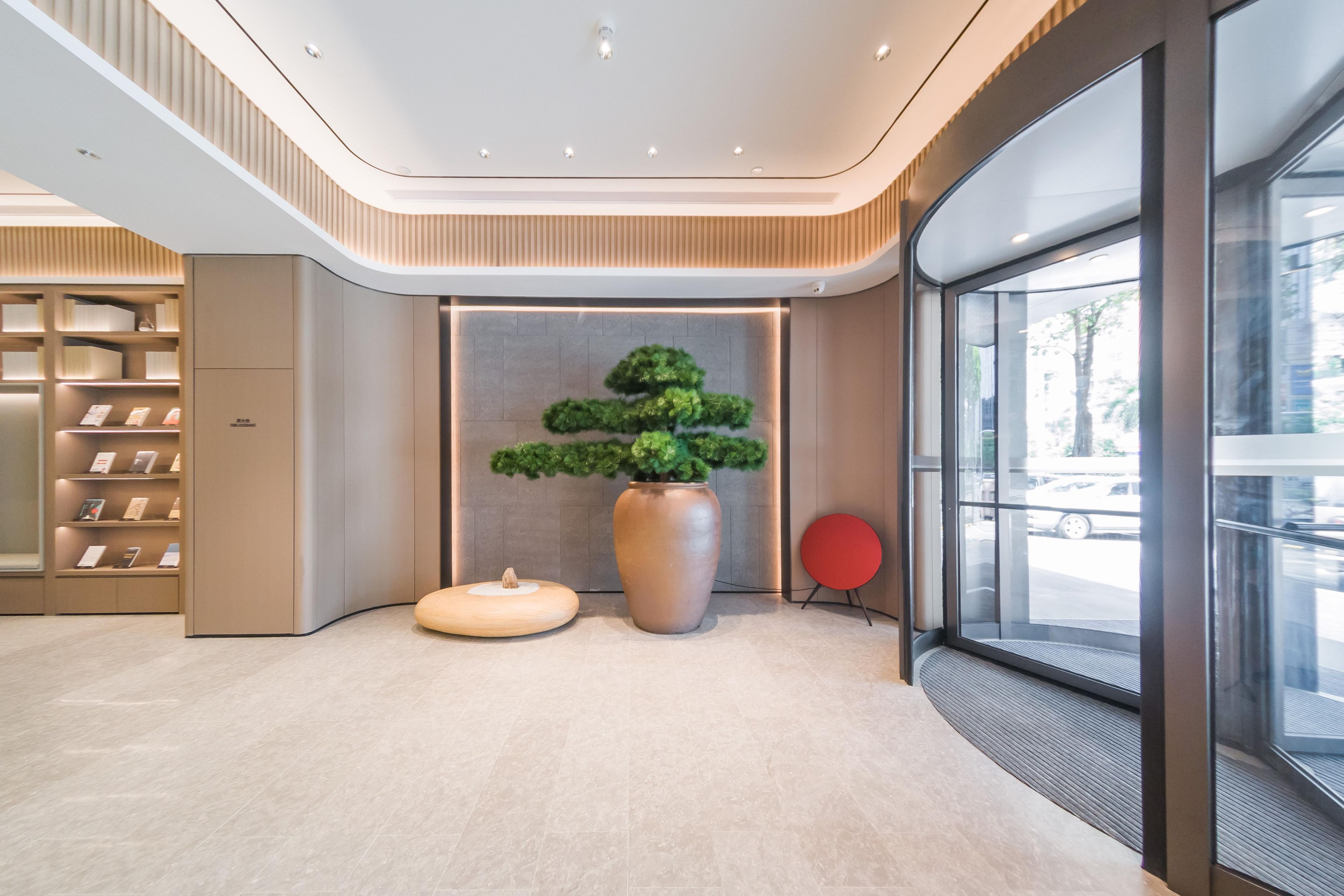 A modern lobby with a central plant display, a seating area, and a glass entrance.
