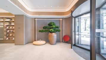 A modern lobby with a central plant display, a seating area, and a glass entrance.