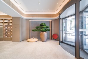 A modern lobby with a central plant display, a seating area, and a glass entrance. - Ji Hotel Shenzhen Baoan Pingzhou Subway Station (Shenzhen)