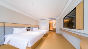Ein modernes Hotelzimmer mit zwei Betten, einem großen Spiegel und einem Fernseher.