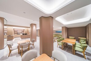 A modern dining area with tables and chairs, a kitchen in the background, and a unique ceiling design. - Ji Hotel Shenzhen Baoan Pingzhou Subway Station (Shenzhen)