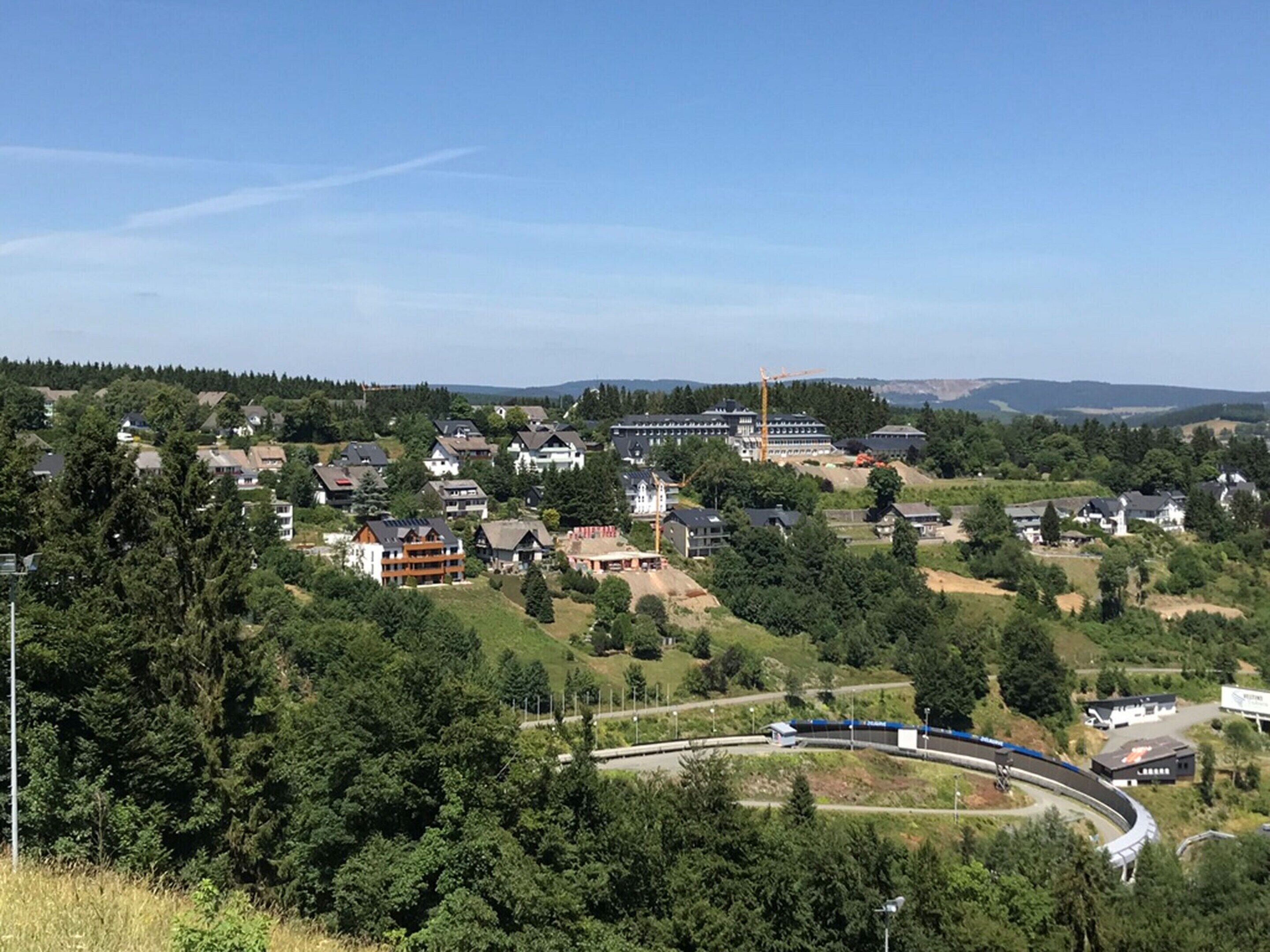 A residential area with houses, a train track, and a large building with a crane.
