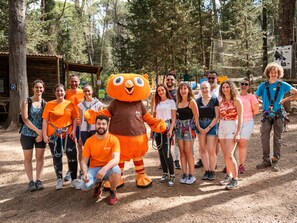 A group of people in an outdoor setting with a mascot, surrounded by trees and a wooden structure. - VVF Villages Montagnac (Montagnac)