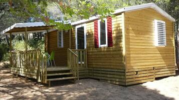 A wooden cabin with a porch and a covered seating area.