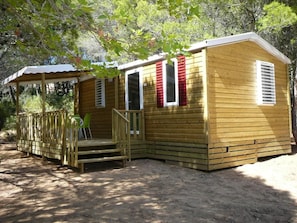 A wooden cabin with a porch and a covered seating area. - VVF Villages Montagnac (Montagnac)