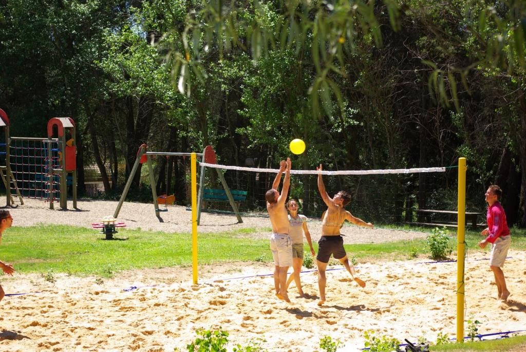 A beach volleyball game with players in action, a net, and a sandy court.