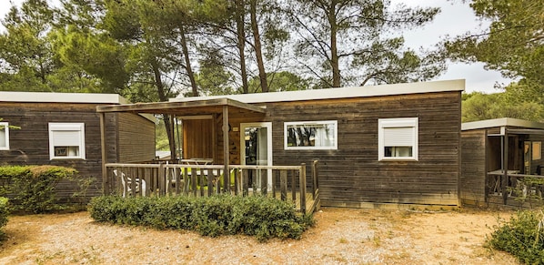 A wooden cabin with a porch, a door, and windows. - VVF Villages Montagnac (Montagnac)