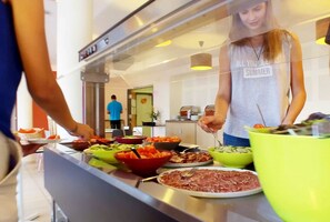 Montaje de bufé con diferentes alimentos y una persona sirviendo.