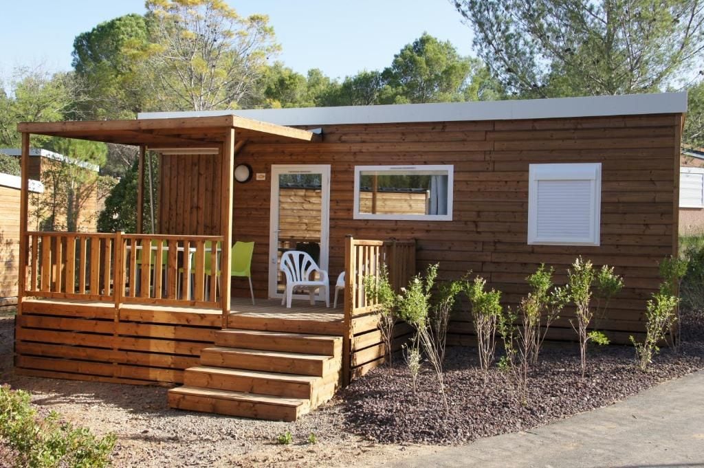 Une cabane en bois avec une véranda, une petite terrasse et une fenêtre.