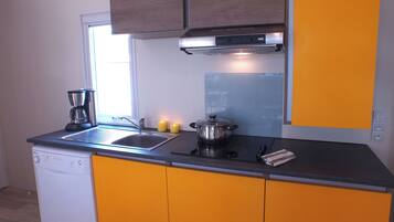 A kitchen with a dishwasher, a coffee maker, a stove, and a pot on the counter.