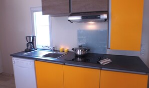 Una cocina con lavavajillas, cafetera, estufa y una olla sobre la encimera.