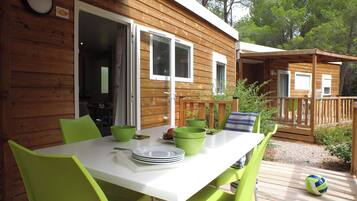 A wooden cabin with a dining table and chairs, a volleyball, and a deck.